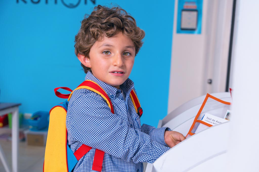 Niño entregando sus tareas en un centro Kumon, listo para continuar su aprendizaje con el método individualizado