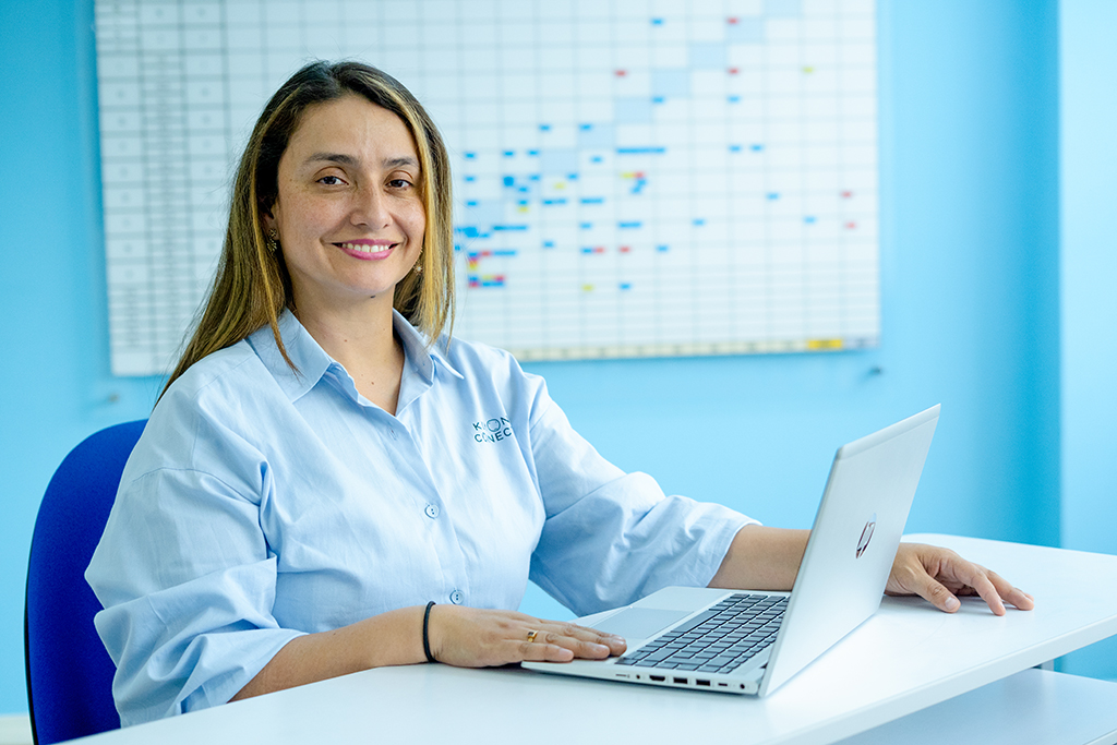 Orientadora sentada delante de una laptop, sonriendo a la cámara y alegre por formar parte de Kumon