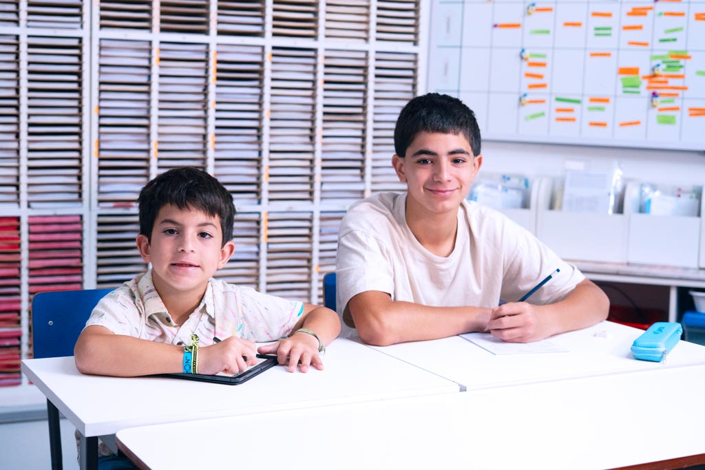 Dos alumnos en un centro Kumon, uno en la tableta y otro en el cuadernillo en papel