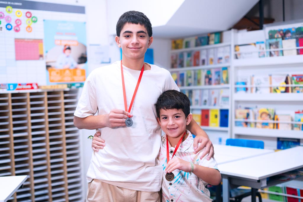 Dos estudiantes en un centro Kumon mostrando orgullosamente sus medallas por logros educativos