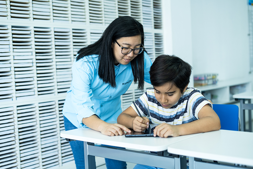Orientador guiando a un estudiante mientras utiliza una tableta para el aprendizaje individualizado en el aula
