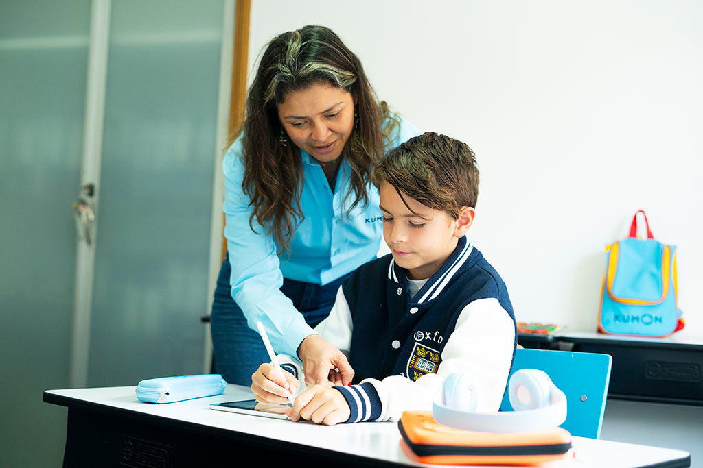 Orientadora de Kumon guiando a um alumno mientras trabaja en tableta