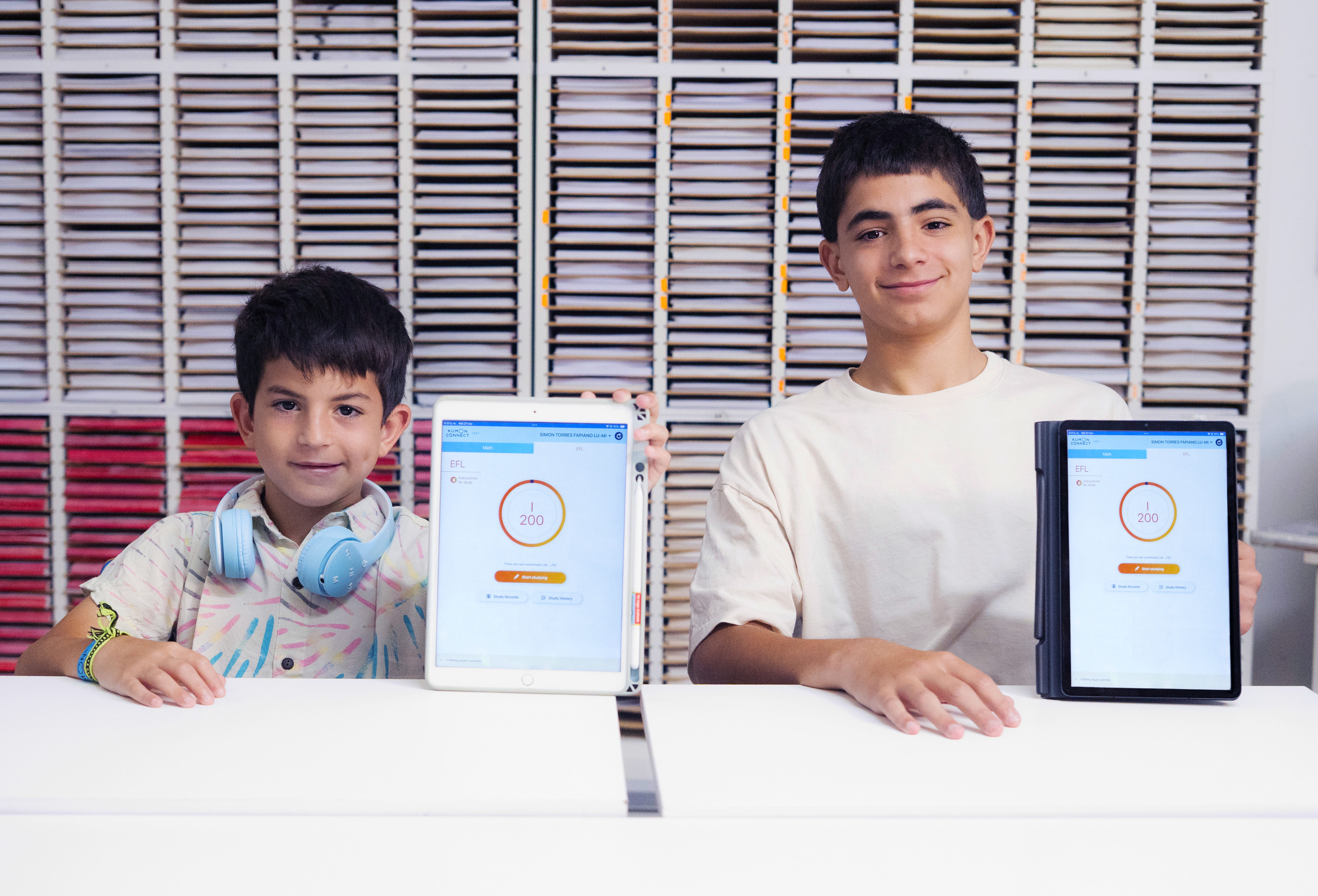 Dos estudiantes mostrando sus avances en tabletas mientras aplican el método Kumon de estudio individualizado